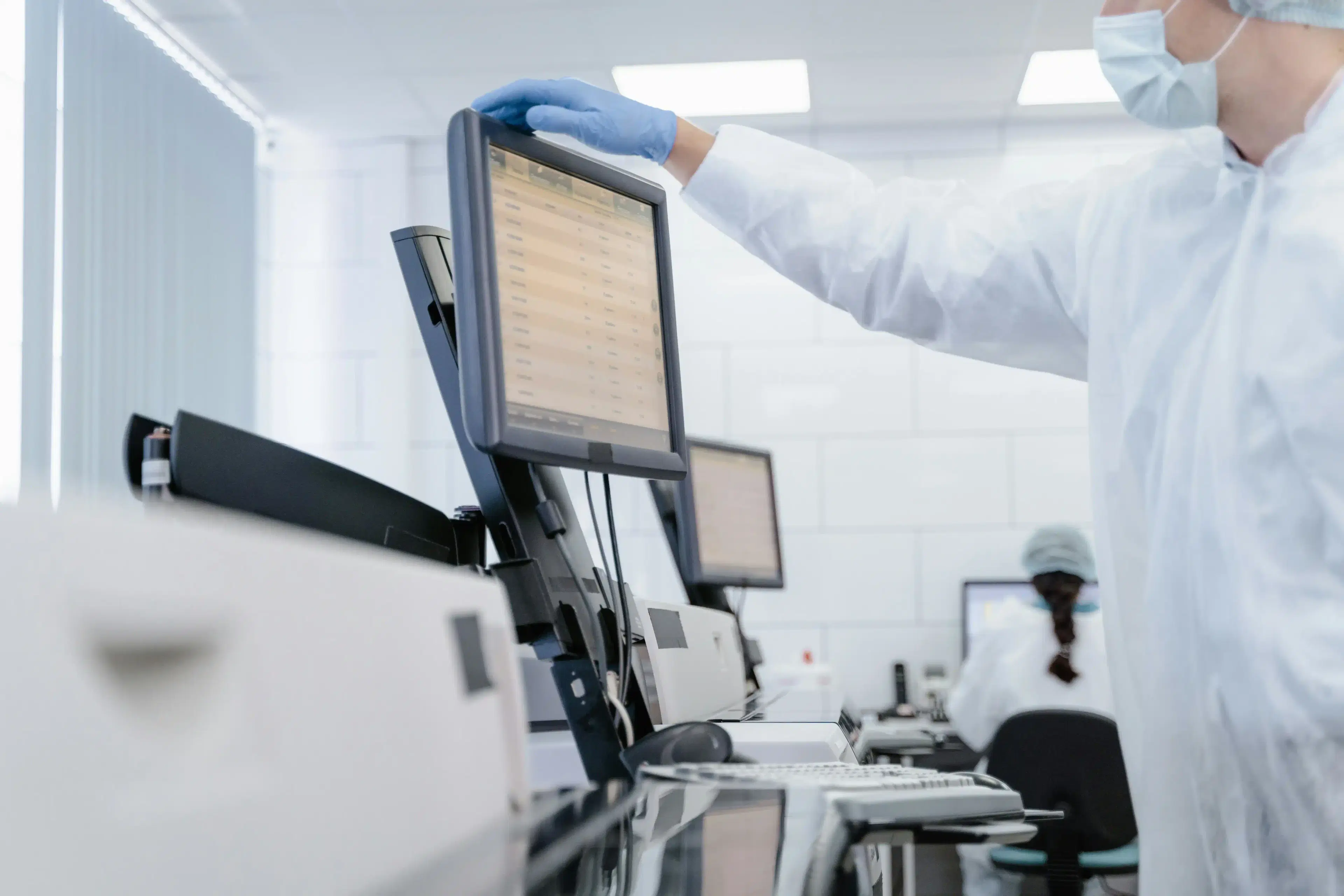 Scientist in protective equipment reviewing data on a laboratory screen